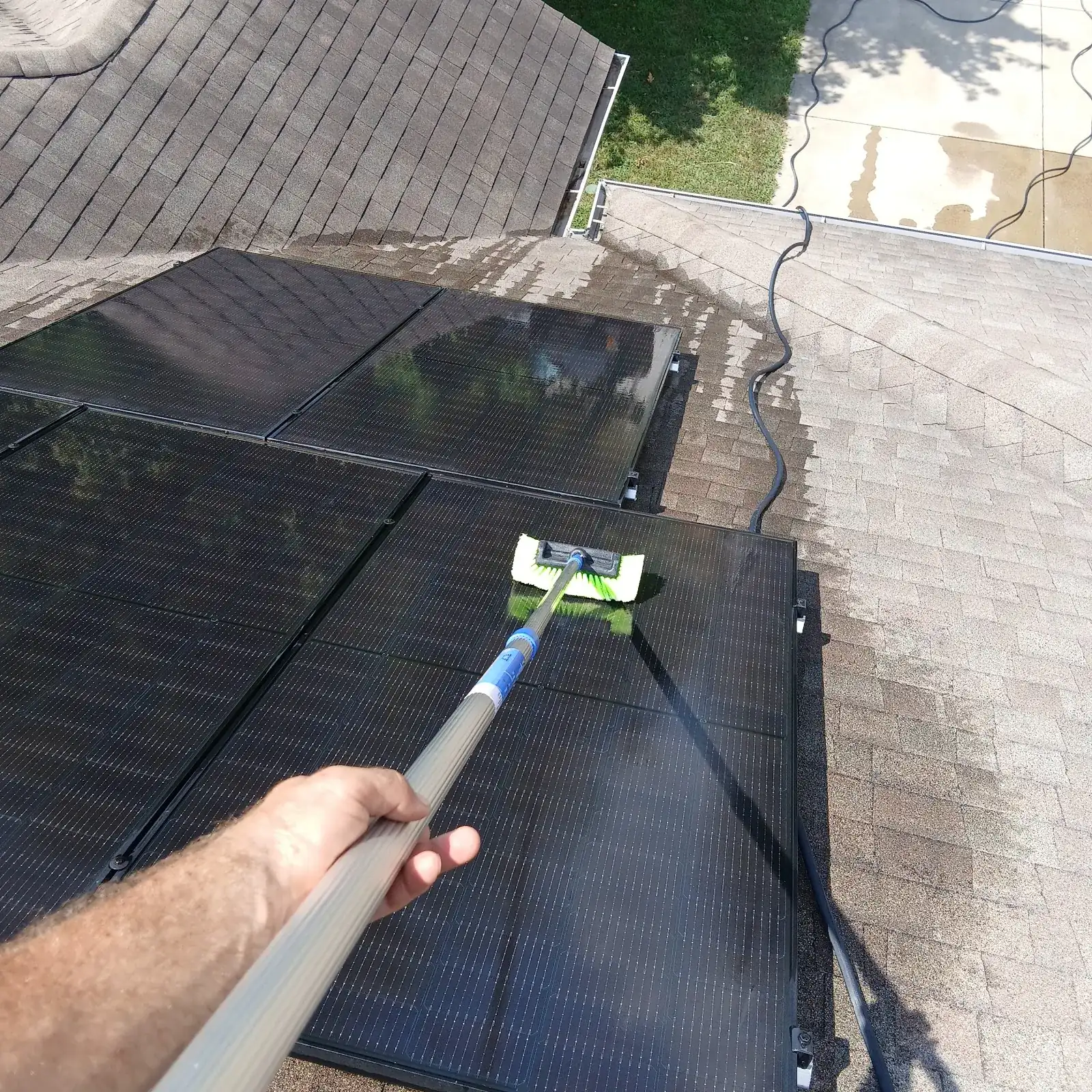 A technician cleaning rooftop solar panels with a squeegee